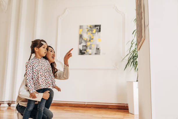 Mother and daughter in modern art gallery looking at paintings.